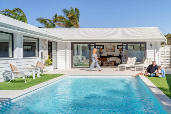 Woman walks by pool towards family in beautifully designed commercial property, The Resort.